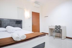a bedroom with a bed and a desk with towels at wisma delapan Mitra RedDoorz in Jakarta