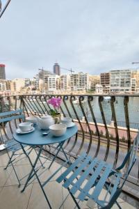 una mesa azul y sillas en un balcón con vistas al agua en Morina Court - St Julians Seaside Bliss Apartments and Penthouse by ShortletsMalta, en San Julián