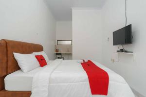 um quarto com uma cama com um cobertor vermelho e branco em RedDoorz Syariah near Exit Toll Jatiwarna 2 em Pondokmelati