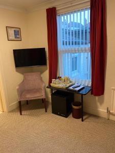 a room with a desk with a chair and a window at The Kingswood Guest House - Adult Only in Weymouth +32 photos