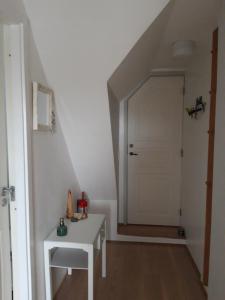 a hallway with a white table and a white door at Skovboferie Apartments BB in Blåhøj Stationsby