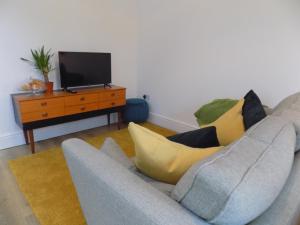 ein Wohnzimmer mit einem Sofa und einem TV in der Unterkunft Villa Mimosa 4 in Cardiff