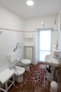 een badkamer met 2 toiletten, een wastafel en een tapijt bij Le case di Elisa 3 in Genua