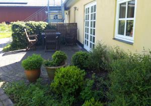 een patio met een tafel, stoelen en planten bij Skovboferie Apartments BB in Blåhøj Stationsby