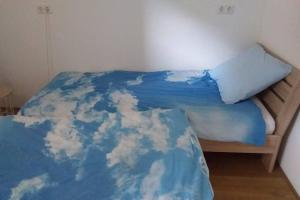 a bed with a blue blanket with clouds on it at Huis bij de Catalpa in Dordrecht