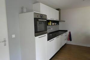 a white kitchen with a sink and a microwave at Huis bij de Catalpa in Dordrecht