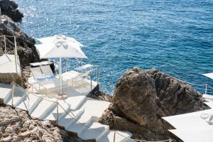 a group of chairs and umbrellas next to the ocean at Villa Dubrovnik in Dubrovnik
