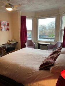 a bedroom with a large bed and two windows at The Kingswood Guest House - Adult Only in Weymouth