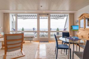ein Wohnzimmer mit einem Tisch und Stühlen sowie einem großen Fenster in der Unterkunft Ferienwohnung Seeblick in Schilksee