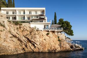 a building on a cliff next to the water at Villa Dubrovnik in Dubrovnik