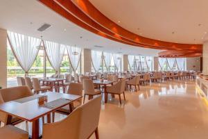 a dining room with tables and chairs and windows at Ramada by Wyndham Kunming YiLiang in Yiliang