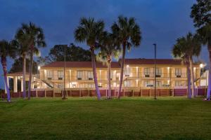 a large building with palm trees in front of it at Super 8 by Wyndham Crestview in Crestview