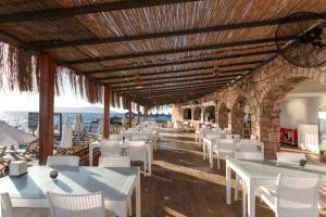 a restaurant with white tables and chairs and the ocean at Vega Aparts in Gümüşlük