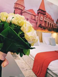 a person holding a bouquet of flowers in front of a castle at YMY Boutique Residence in Bucharest