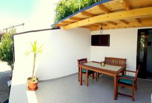 a patio with a wooden table and chairs and a plant at Apartmani Tina in Jelsa