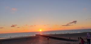 a sunset at the beach with people walking on the beach at MEERzeit-Norderney in Norderney