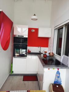 a kitchen with white cabinets and red accents at Cap Est in Le Moule