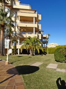 a large building with palm trees in front of it at GOLF Y MAR - Oliva Nova in Oliva