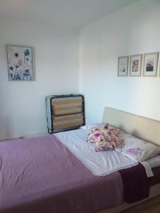 een slaapkamer met een bed met paarse lakens en foto's aan de muur bij Apartmani Tina in Jelsa