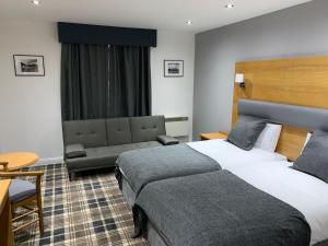 une chambre d'hôtel avec deux lits et un canapé dans l'établissement Crowwood Hotel and Alba Restaurant, à Chryston