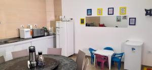 a kitchen with a table and chairs and a refrigerator at Maragogi Suítes in Maragogi