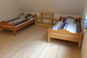 Duas camas num quarto com pisos em madeira em Große Ferienwohnung auf Pferdehof Mitten in der Natur 