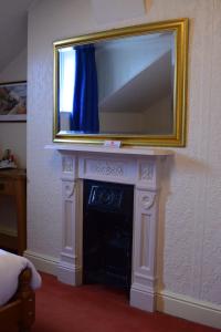 a fireplace with a mirror above it with a television over it at Bewdley Hill House in Kidderminster