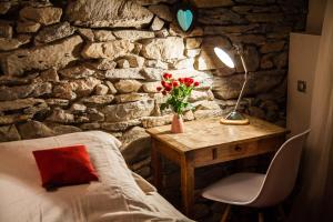 Habitación con paredes de piedra, mesa, cama y escritorio con flores. en Versaya, en Bourg-Saint-Maurice