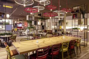 a restaurant with a large wooden table and chairs at IntercityHotel Hildesheim in Hildesheim