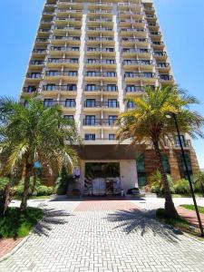 a large building with palm trees in front of it at Matiz Multi Suites in Duque de Caxias