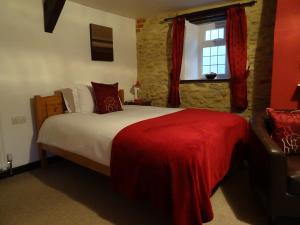 a bedroom with a bed with a red blanket and a window at Quiet Woman House in Halstock