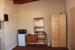 a room with a desk and a refrigerator and a mirror at Oasis Motel in Antigonish