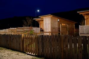 ein Holzzaun vor einem Haus in der Nacht in der Unterkunft Les Lodges de la ViaRhôna / cabane-spa in Virignin