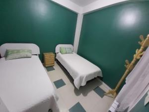 Habitación con 2 camas y pared verde. en Residencial Hinojosa, en Oruro