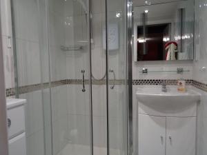 een witte badkamer met een douche en een wastafel bij Quiet Woman House in Halstock