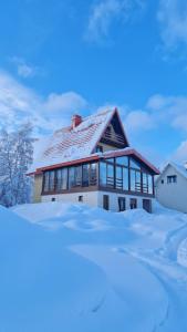 dom pokryty śniegiem z przodu w obiekcie Borovnica Sweet Apartments w mieście Žabljak