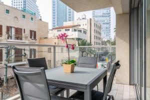 una mesa y sillas en un balcón con una flor. en Amazing 3Bedrooms 2 Baths Balcony and Parking PRV, en Tel Aviv