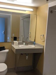 W łazience znajduje się umywalka, toaleta i lustro. w obiekcie Harbor Inn w mieście Wrightsville Beach