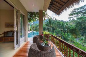 balcón con sillas de mimbre y vistas a la piscina en Surya Shanti Villa Sidemen, en Sidemen