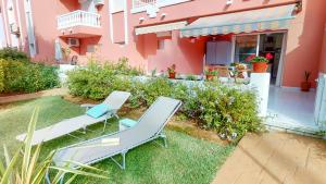 two chairs and a table in front of a pink house at Apartamento Jazmin by Family Homes in Denia