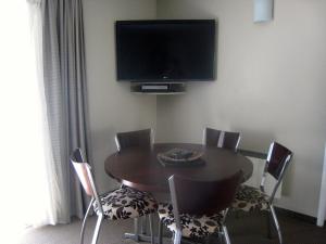 a dining room table with chairs and a television on the wall at Buller Court on Palmerston in Westport