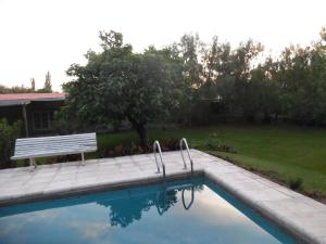 a swimming pool with a bench next to a yard at Casas de Campo Los Corralitos in Mendoza +6 photos
