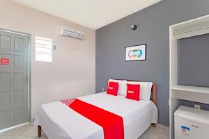 Schlafzimmer mit einem weißen Bett und roten Kissen in der Unterkunft OYO Pousada Horizonte in Horizonte