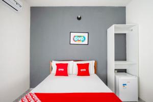 a bedroom with a white bed with red pillows at OYO Pousada Horizonte in Horizonte