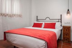 コニル・デ・ラ・フロンテーラにあるHabitaciones y Apartamentos en el centro La Jábega by Conil Homeのベッドルーム1室(大型ベッド1台、赤い枕付)