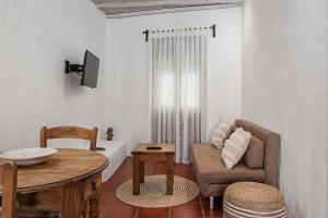 ein Wohnzimmer mit einem Stuhl und einem Tisch in der Unterkunft Habitaciones y Apartamentos en el centro La Jábega by Conil Home in Conil de la Frontera