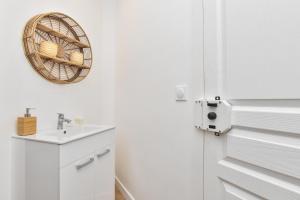 La salle de bains est pourvue d'un lavabo et d'un panier en osier sur le mur. dans l'établissement Superbe appartement 6P rue des Martyrs, à Paris