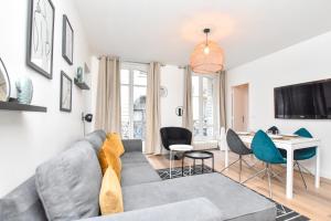 un soggiorno con divano grigio e sedie di Superbe appartement 6P rue des Martyrs a Parigi
