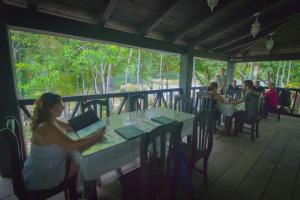 grupa ludzi siedzących przy stole na pokładzie w obiekcie Ecolodge Las Nubes Chiapas w mieście La Fortuna Gallo Giro
