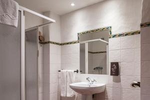 ein weißes Badezimmer mit einem Waschbecken und einem Spiegel in der Unterkunft Habitaciones y Apartamentos en el centro La Jábega by Conil Home in Conil de la Frontera